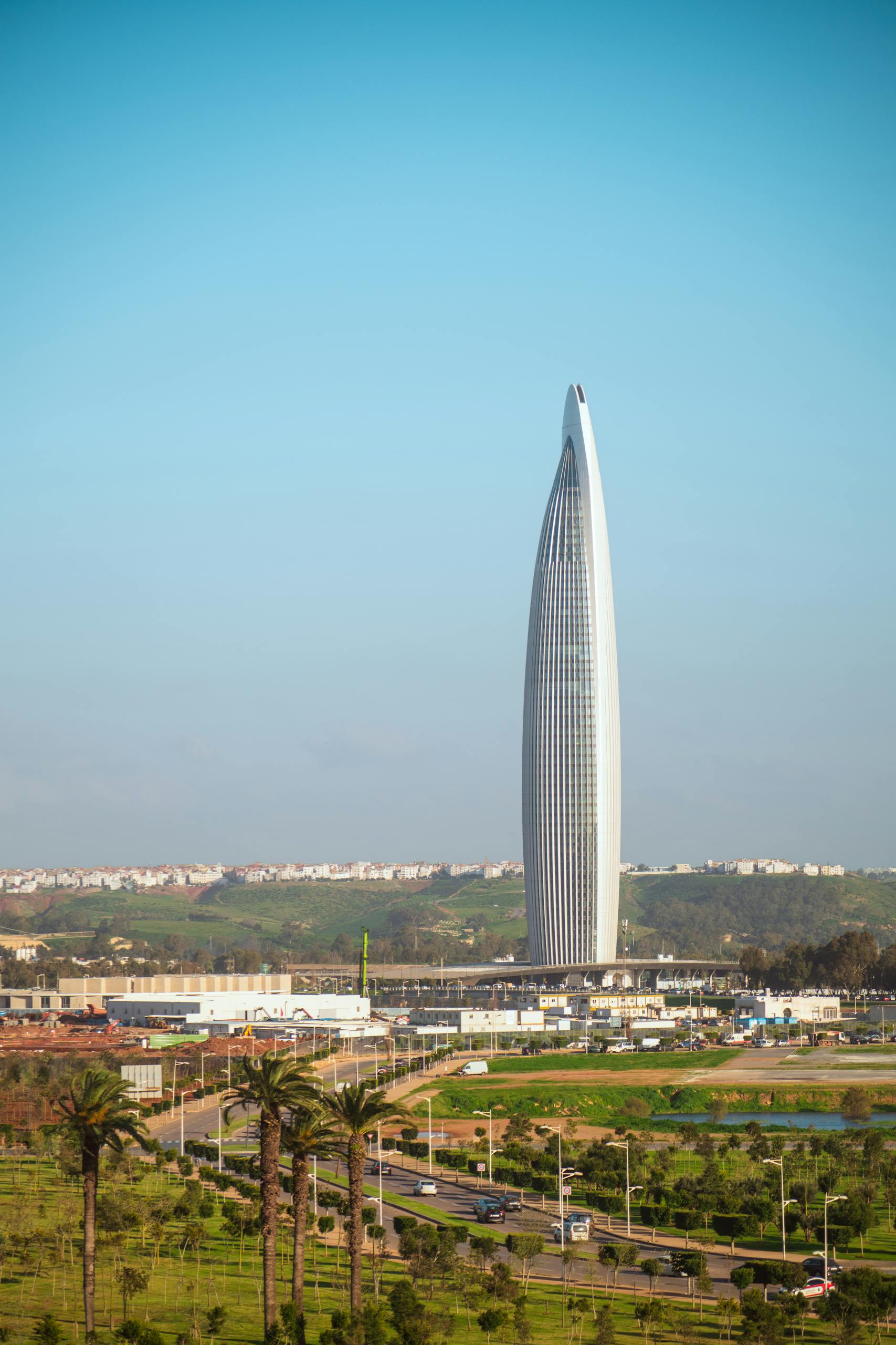 A modern skyscraper in Rabat, Morocco stands against a blue sky, surrounded by greenery.
