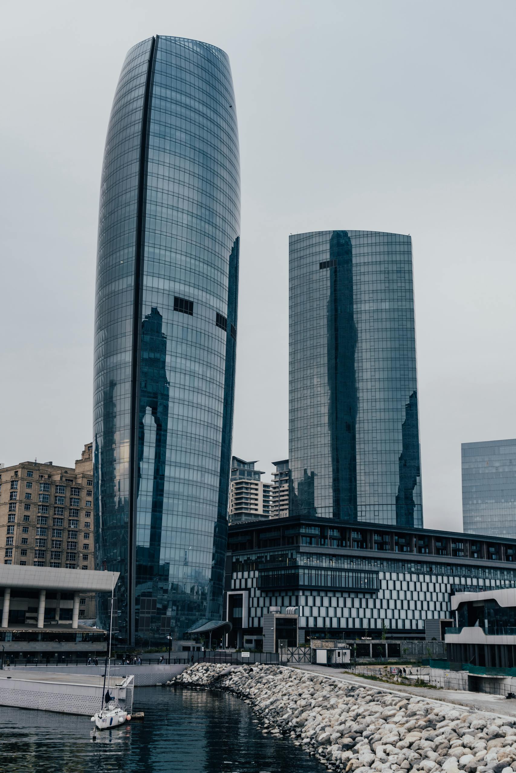 A towering modern skyline featuring glass skyscrapers by a tranquil waterfront.