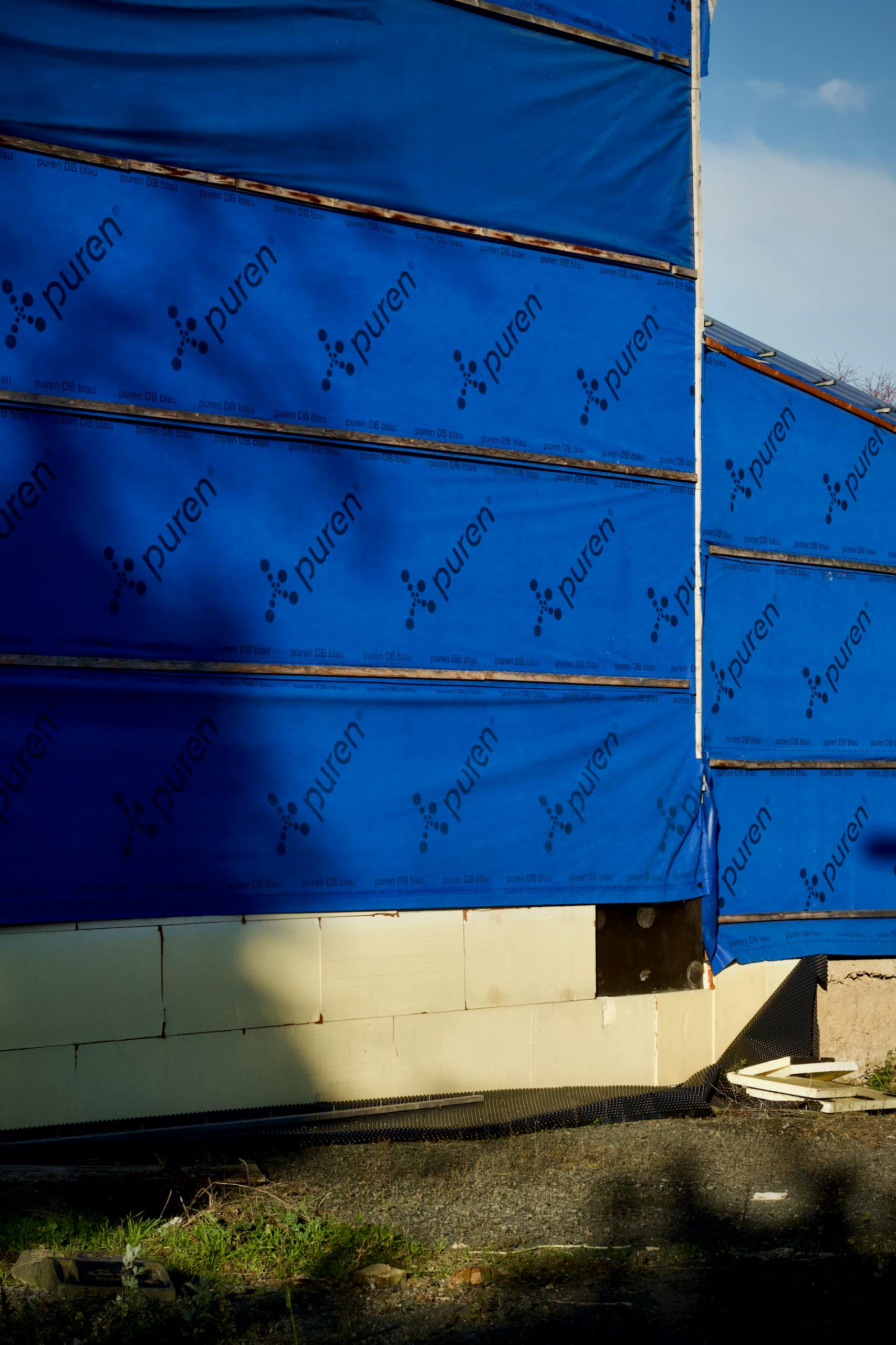 Building under construction with blue insulating wrap showing brand name puren